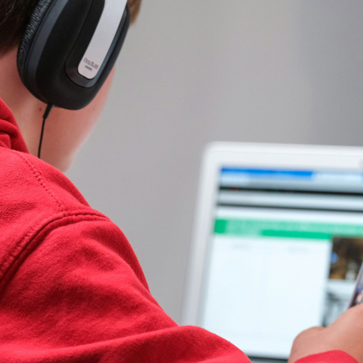 Tiener met koptelefoon oefent online voor het auto theorie examen op een laptop