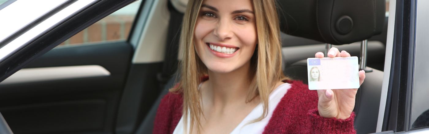 Vrouw toont trots haar rijbewijs na het online oefenen van het auto theorie examen