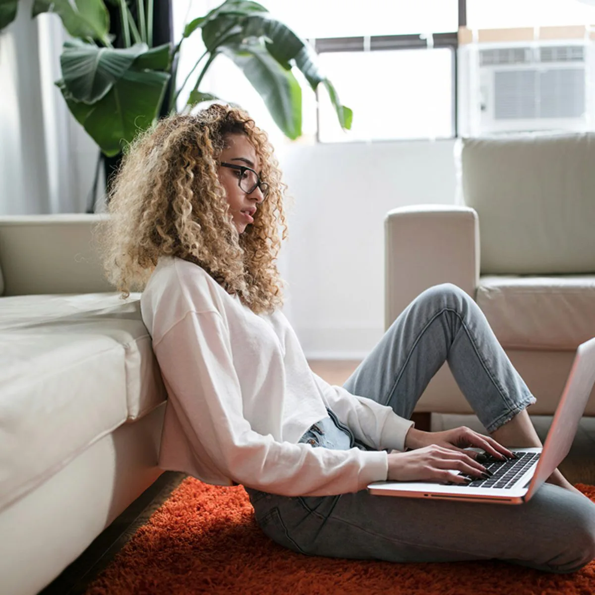 Vrouw met een laptop op de vloer bereidt zich voor op het theorie examen